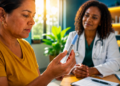 Mulher observa uma caneta de aplicação de medicamento durante consulta com uma médica