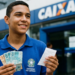 Estudante sorri segurando notas de real e um comprovante e, ao redor, a fachada azul de uma agência da Caixa