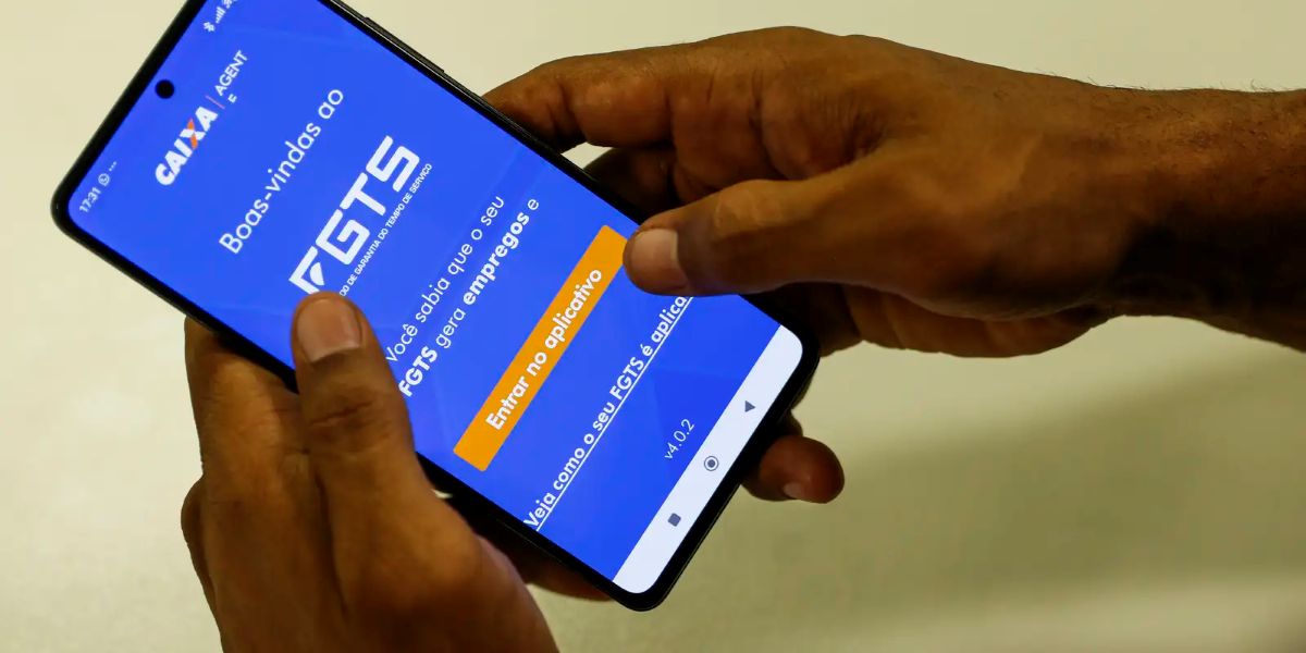 Mãos seguram celular com a tela de boas-vindas do aplicativo FGTS da Caixa aberta