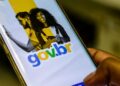 Mão segura um celular com a tela do aplicativo Gov.br