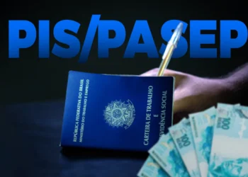 Carteira de trabalho e cédulas de cem reais sobre uma mesa, com a inscrição PIS/Pasep ao fundo, em referência ao ressarcimento das cotas do antigo fundo em 2026.