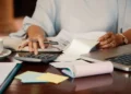 Desenrola Brasil 2.0: imagem ilustrativa de pessoa organizando boletos com calculadora, notebook e caderno, em referência ao processo de simulação de descontos previstos no programa de renegociação de dívidas