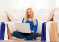 Mulher sorrindo enquanto realiza compras online pelo notebook