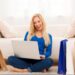 Mulher sorrindo enquanto realiza compras online pelo notebook