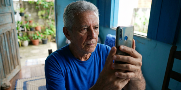 Aposentado utiliza celular em casa para realizar a biometria facial