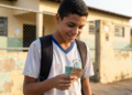 Estudante de uniforme sorri segurando notas de real e, ao redor, a fachada de uma escola