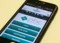 Smartphone exibindo o site oficial do Banco Central com informações sobre o Pix, sistema de pagamentos instantâneos no Brasil, alvo de fraudes e golpes digitais.
