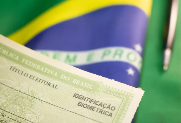 Título eleitoral brasileiro com identificação biométrica sobre a bandeira do Brasil em cores verde, amarela e azul.