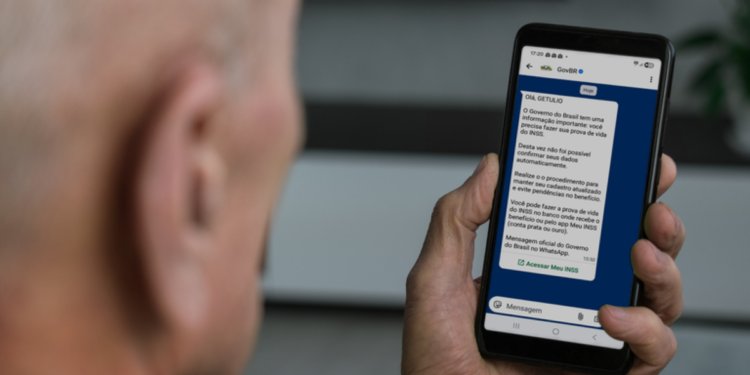 Aposentado lê no celular mensagem oficial do governo sobre a Prova de Vida do INSS pelo WhatsApp do GovBR