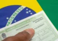 Mão segurando título eleitoral do Brasil com campo de biometria sobre bandeira verde e amarela.