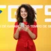 Mulher jovem sorridente vestindo vermelho e segurando um smartphone em frente a um fundo amarelo com o logotipo branco do FGTS e a inscrição "Fundo de Garantia do Tempo de Serviço".