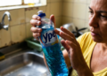 Mulher observa atentamente um frasco de detergente da marca Ypê