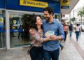 Casal feliz segura notas de reais ao sair da agência do Banco do Brasil no centro urbano