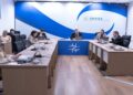 Diretoria da Anvisa reunida em sala de reuniões oficial com logomarca azul ao fundo e computadores sobre a mesa