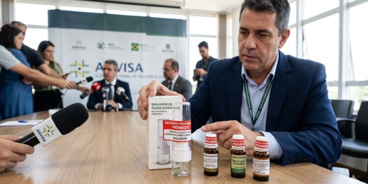 Homem exibe inalador e frascos rotulados como proibidos em mesa com microfones da Anvisa, coletiva ao fundo