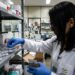 Agente técnica da Anvisa com jaleco branco inspeciona frascos de tirzepatida em prateleira de farmácia hospitalar vinculada ao SUS.