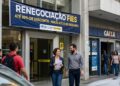 Grupo de pessoas em frente à agência da Caixa com faixa sobre FIES e descontos de até 99%