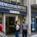 Grupo de pessoas em frente à agência da Caixa com faixa sobre FIES e descontos de até 99%