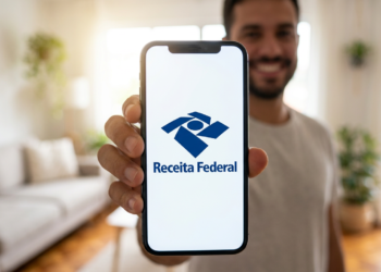 Homem exibe aplicativo Receita Federal aberto no smartphone em casa.