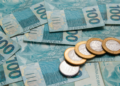 Notas de 100 reais e moedas de 1 real.