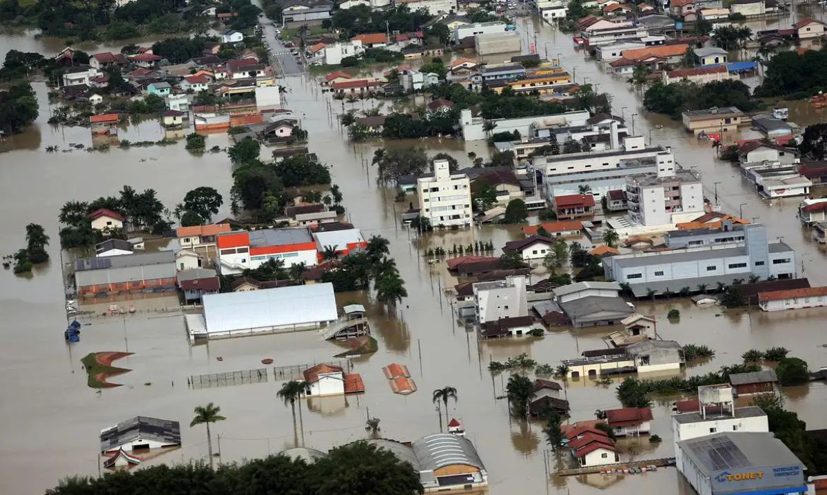 Vista aérea de bairro urbano inundado com ruas, casas e prédios parcialmente cobertos pela água