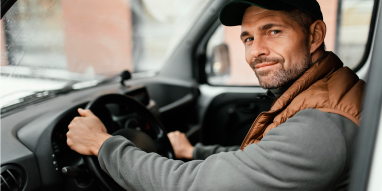 Motorista de boné sorrindo ao volante dentro de veículo utilitário.