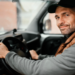 Motorista de boné sorrindo ao volante dentro de veículo utilitário.
