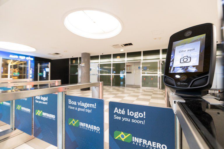 Equipamento de biometria facial com visor "Olhe aqui" em portão de embarque Infraero