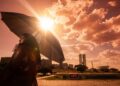 Mulher negra segura guarda-chuva sob sol intenso com termômetro marcando 43°C e Congresso Nacional ao fundo em Brasília