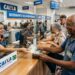 Idoso recebe dinheiro de atendente da Caixa com fila de aposentados ao fundo em ambiente bancário