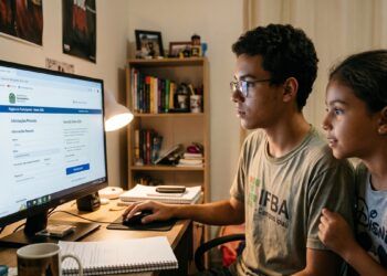 Adolescente com camiseta do IFBA faz inscrição do Enem em computador ao lado de menina