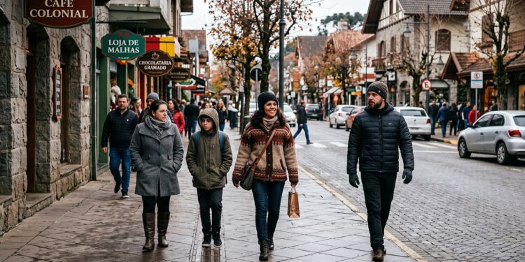 Grupo de quatro pessoas com roupas de frio caminha pelo centro de Gramado, com lojas e placas visíveis ao fundo