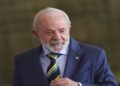 Lula com terno azul e gravata verde-amarela em ambiente oficial, sorrindo discretamente