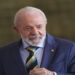 Lula com terno azul e gravata verde-amarela em ambiente oficial, sorrindo discretamente