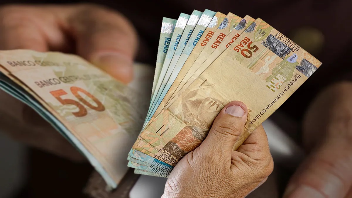 Mãos segurando notas de 50 reais e outras cédulas brasileiras, foco em dinheiro