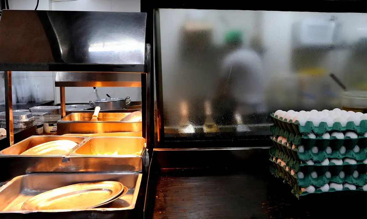Cozinha de restaurante com ovos empilhados e bancada aquecida em aço inox
