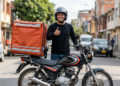 Entregador de aplicativo faz sinal positivo com mochila térmica na moto.