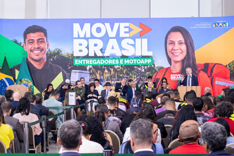 Move Brasil Entregadores dá desconto para mulheres: taxa máxima cai para 10,25% ao ano no financiamento 2 Público assiste a autoridades em palco com painel do Move Brasil Entregadores e destaque para entregadora mulher