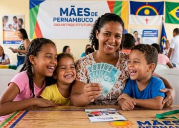Mulher sorridente mostra notas de 100 reais junto a três crianças em evento do Mães de Pernambuco