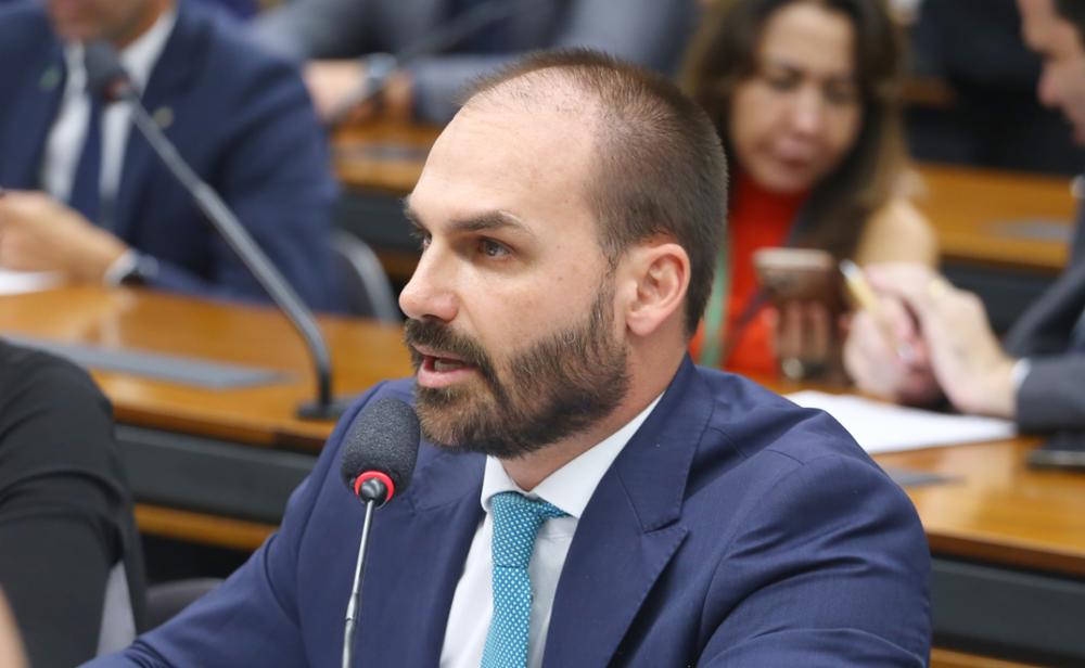 Eduardo Bolsonaro, de terno azul, fala ao microfone durante sessão na câmara dos deputados