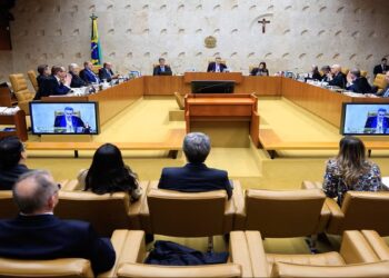 Ministros do STF sentados em sessão plenária, com telões exibindo autoridade discursando