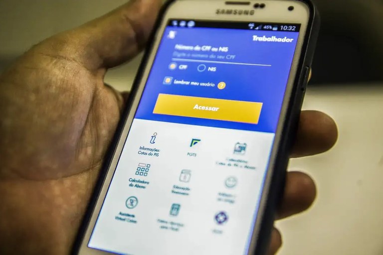 Mão segurando celular Samsung com aplicativo FGTS aberto na tela de login com campos CPF e NIS