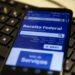 Smartphone exibindo site da Receita Federal sobre teclado preto em ambiente de trabalho