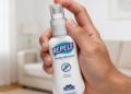 Mão segurando frasco do repelente REPELE com rótulo azul em sala iluminada.