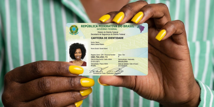Mãos femininas com unhas amarelas segurando Carteira de Identidade Nacional do Distrito Federal com foto de mulher.