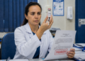 Médica de jaleco analisa frasco de PMMA com seringa e segura resolução marcada como proibido