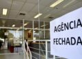 Aviso de agência fechada colado na porta de vidro de banco durante feriado