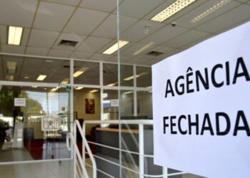 Aviso de agência fechada colado na porta de vidro de banco durante feriado