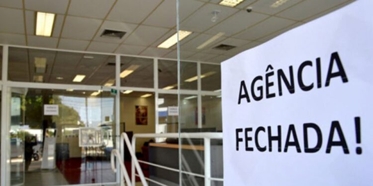 Aviso de agência fechada colado na porta de vidro de banco durante feriado