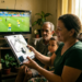 Família observa o kit da antena digital do Brasil Antenado enquanto assiste a um jogo de futebol na TV.
